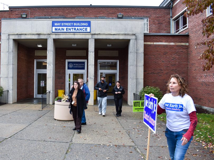 Photo Caption: Laura Foster (right) stands outside the May Street Building at Worcester State as early voters walk in and out. She and several other people stood outside holding signs for various candidates, Nov. 2, 2018. Photo by Zachary Eilert